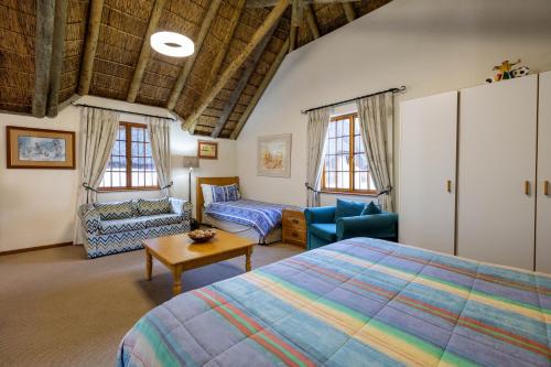 a bedroom with a bed and a couch and a table at Plotsklaps Self Catering Cottage in Tokai