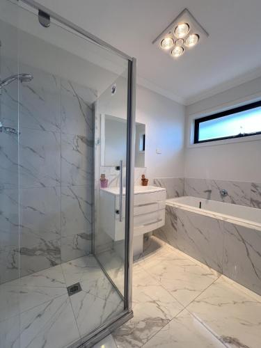 a bathroom with a glass shower and a tub at Matthews Green fall House in Sunshine