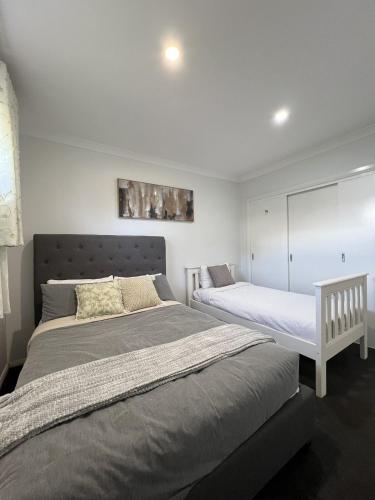 two beds in a bedroom with white walls at Matthews Green fall House in Sunshine