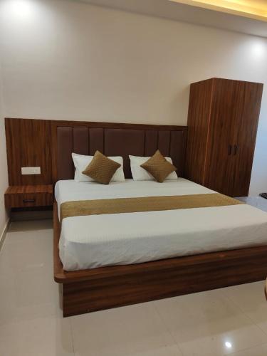 a bedroom with a large bed with a wooden headboard at Hotel Shree Krishnam, Kota in Kota