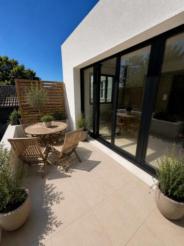 a patio with a table and chairs and windows at Maison Plumeria in Triel-sur-Seine