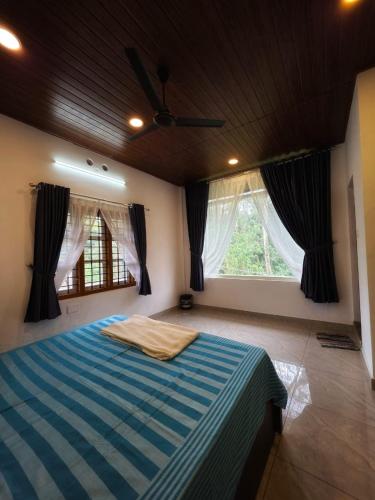 a bedroom with a large bed with a blue striped blanket at Pine ridge homestay kuttikanam in Pīrmed