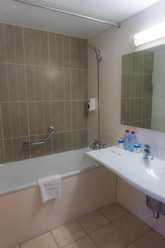 ein Badezimmer mit Badewanne, Waschbecken und Spiegel in der Unterkunft Hôtel Elaïs in Pointe-Noire