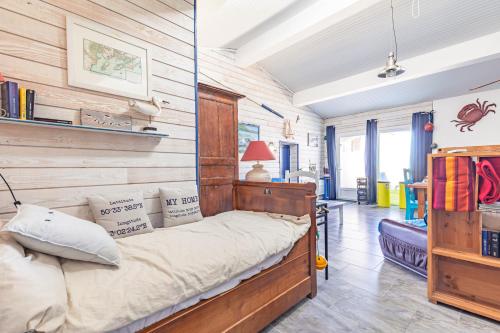 a bed in a room with a wooden wall at Petite Maison Typique in La Cotinière