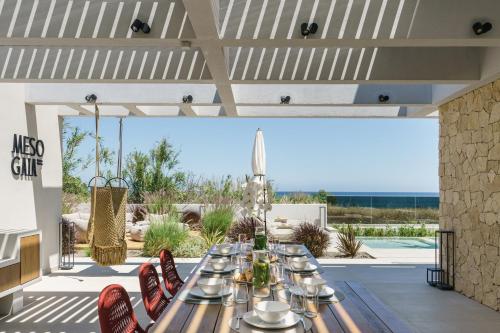 a dining room with a table and chairs on a patio at New Beachfront Mesogaia Villa with Heated Pool, Jacuzzi & Playroom, 60m from the beach in Pigianos Kampos