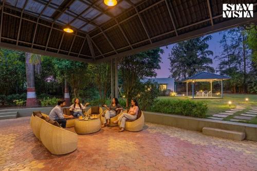 a group of people sitting in chairs on a patio at Hindavi Green Escape by VEO - Part of StayVista with Bonfire, BBQ & Pool in Pune