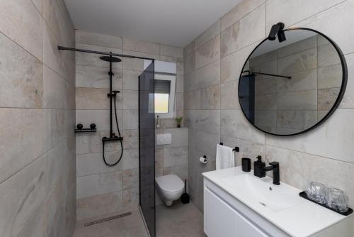 a bathroom with a shower and a sink and a mirror at Apartman Klara in Vrgorac