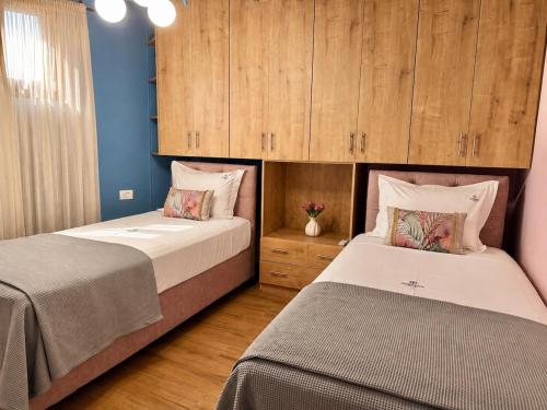 two beds in a bedroom with blue walls and wooden cabinets at Jasemina Luxury Apartment in Agios Nikolaos