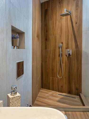a bathroom with a shower with a wooden wall at Jasemina Luxury Apartment in Agios Nikolaos