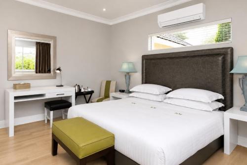 a bedroom with a large white bed and a desk at Vetho Villa in Cape Town