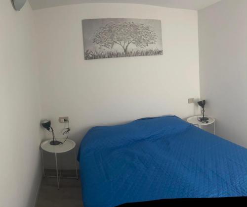 a bedroom with a blue bed and two tables at TAVANIs HOUSE in Delebio
