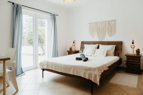 a bedroom with a bed and a large window at Aldeia Caiçara Surf Lodge - Arrifana in Aljezur