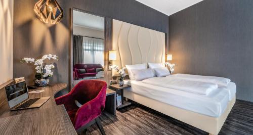 a hotel room with a bed and a desk with a computer at PLAZA INN Heilbronn in Heilbronn