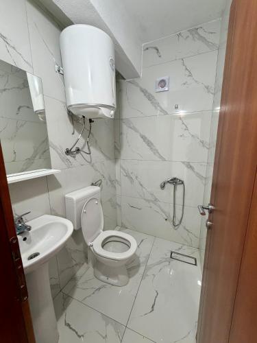 a white bathroom with a toilet and a sink at Molla Apartments in Ulcinj