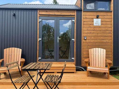 two chairs and a table on the deck of a cabin at Ezy House by Tiny Away in Ézy-sur-Eure