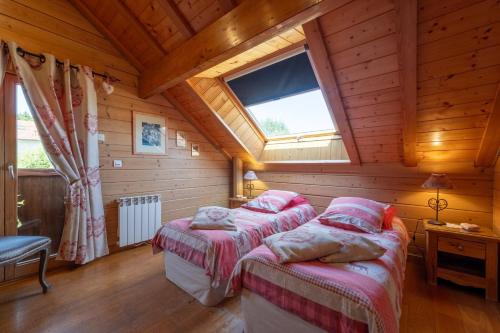 a bedroom with two beds in a wooden house at Chalet Du Pont Des Fées in Gérardmer