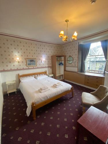 a bedroom with a large bed and a chair at Windermere Bed and Breakfast in Windermere