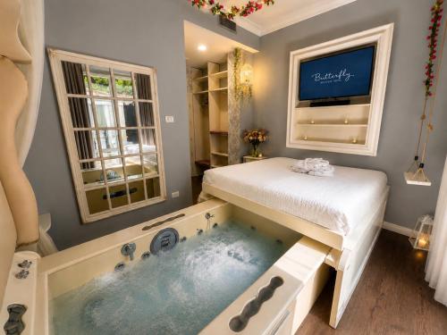 a bedroom with a tub and a bed and a tv at Hotel Butterfly in Torre del Lago Puccini