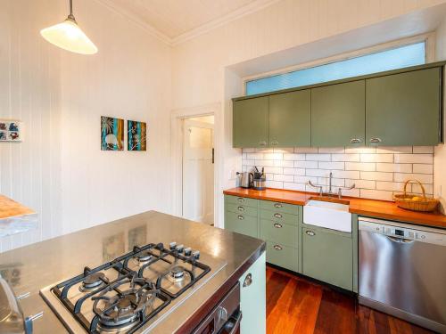 a kitchen with green cabinets and a stove top oven at Crescent Villa - Stay Waiheke in Ostend