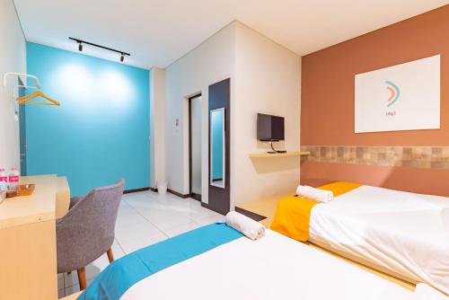a hotel room with a bed and a desk at Sans Hotel Good Wish Semarang in Jomblang