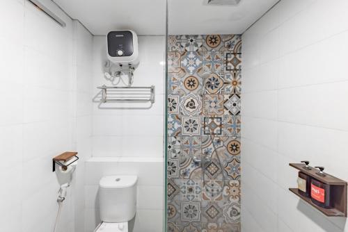 a bathroom with a toilet and a tiled wall at Sans Hotel Good Wish Semarang in Jomblang