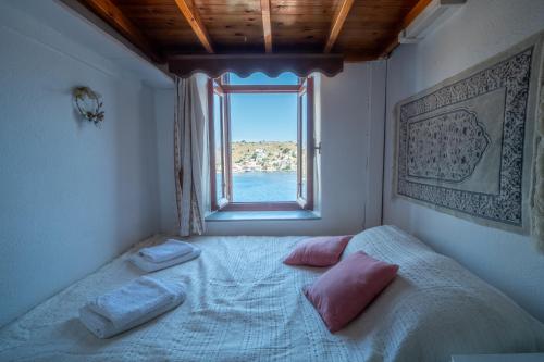 a bedroom with a bed with pink pillows and a window at Villa Pitini in Symi