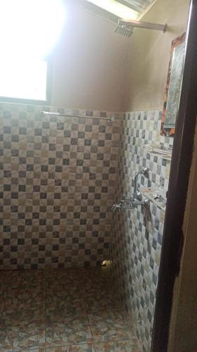 a bathroom with a shower with a tiled wall at The Hojai Farmland in Hāflong