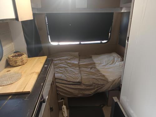 a small bed in a small room with a window at Divine Caravane in Digne-les-Bains
