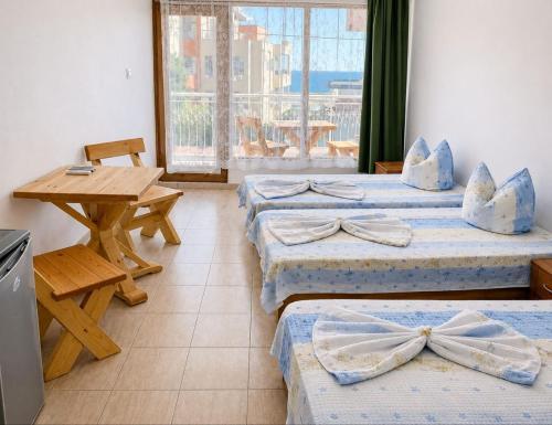 a room with three beds and a table and a window at Къща за гости Уют in Sveti Vlas