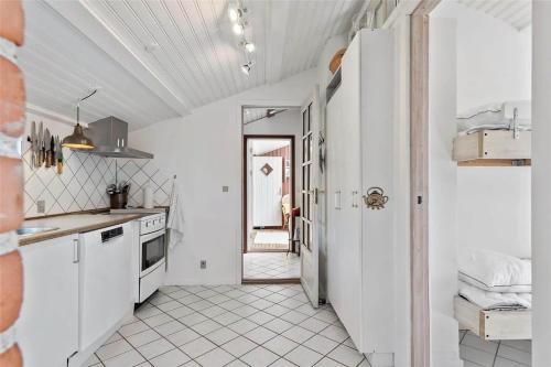 a kitchen with white cabinets and a white tile floor at R624-Rodvig-Stevns-Strandvaenget-6 in Rødvig