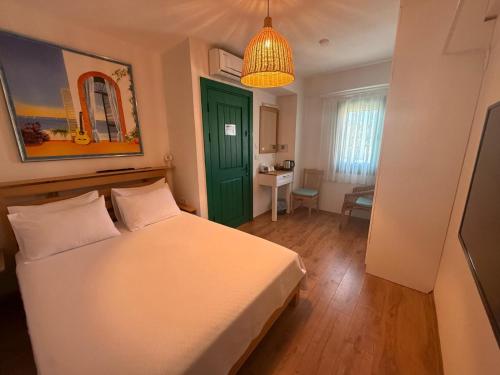 a bedroom with a white bed and a green door at Felicitta Stay & Joy in Seferihisar