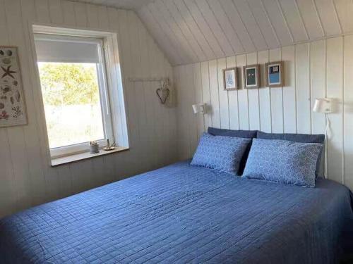 a bedroom with a blue bed with a window at 1335-Vestervig-Spovevej-11 in Vestervig