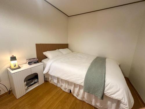 a small bedroom with a white bed and a night stand at The Greenery Omok in Seoul