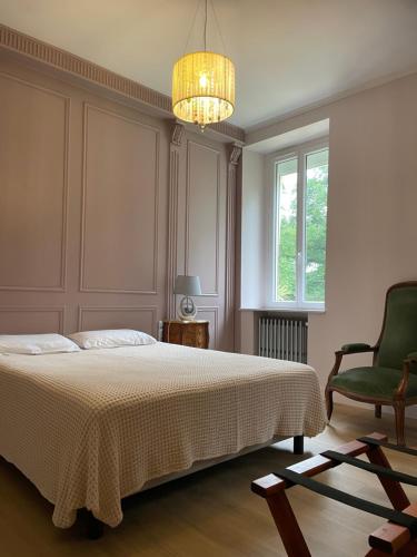 a bedroom with a bed and a chair and a chandelier at La Belle Chartreuse in Manciet
