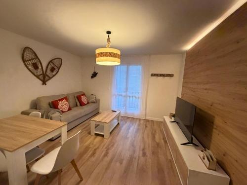 a living room with a couch and a tv and a table at Apartamentos Leyre Candanchú in Candanchú