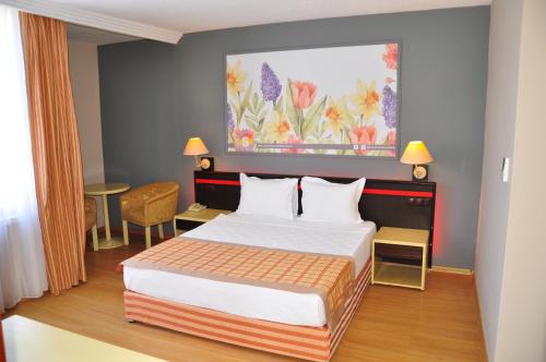 a bedroom with a bed and a painting on the wall at Senza Sunset Beach Hotel in Alanya