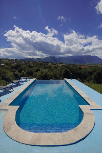 a swimming pool with blue water and mountains in the background at SkyAtlas Hideaway in Sohodol