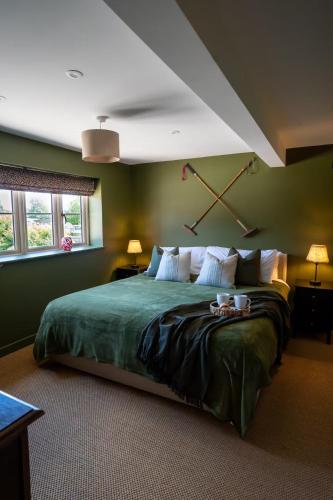 a bedroom with a large green bed with two lamps at The Stable in Clack