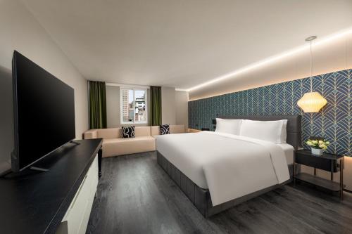 a hotel room with a large bed and a flat screen tv at JingLai Bushe Hotel the Bund Nanjing West Road Shanghai in Shanghai