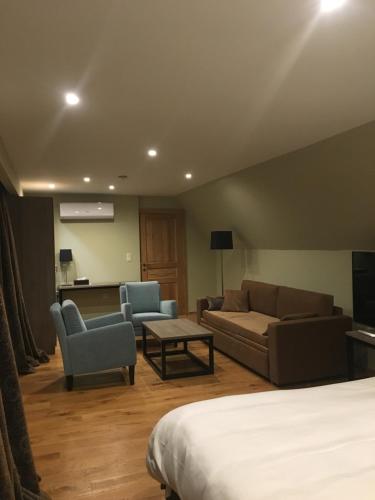 a hotel room with a bed and a couch and chairs at De Gouden Klokke in Avelgem