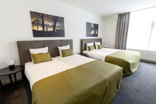 a hotel room with two beds and a table at De Zwaan Delden in Delden