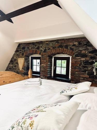 a bedroom with a brick wall and a bed with pillows at Apartmány Haberschie in Řehlovice