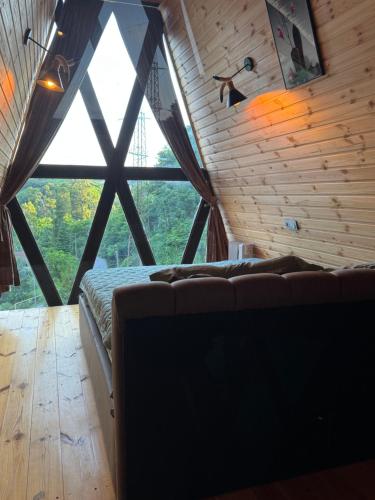 a room with a bed and a large window at Barbare Cottage in Chakvi