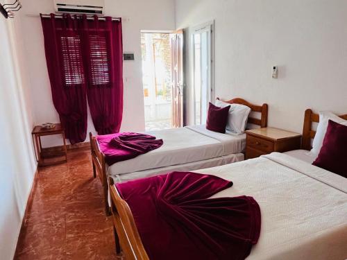 two beds in a room with red curtains at Praia do Sol in Tarrafal