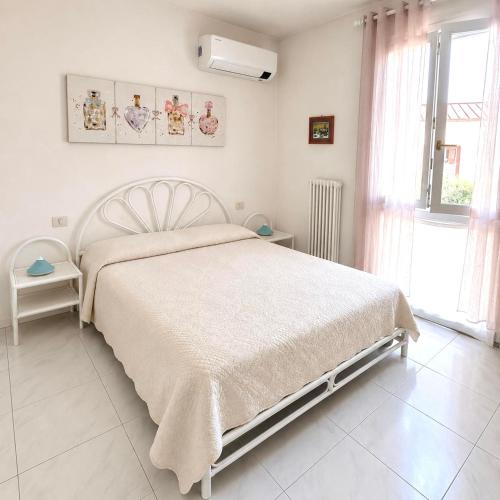 a white bedroom with a bed and a window at Residenz In 1 in Bardolino