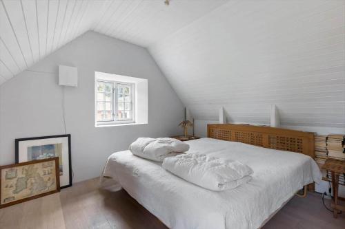 a bedroom with a bed with white sheets and a window at 4263-Stege-Mollebrondstraede-13 in Stege