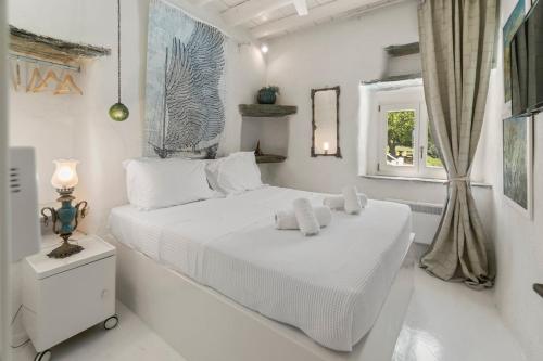 a white bedroom with a bed with towels on it at Nest Gateway - Panoramic Mountain Views in Apoíkia
