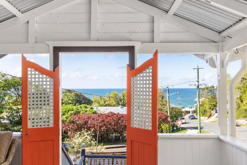 an orange door on a porch with a view of the ocean at Pacific Terrace Beach House in Coolum Beach