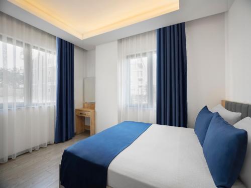 a bedroom with a blue and white bed and windows at Silence Garden Suite bir yatak odalı daire in Alanya