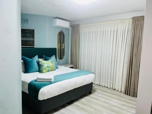 a bedroom with a large bed with blue walls at Hyde Park in Durban